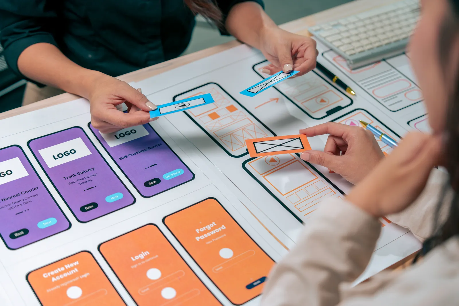 Designers arranging mobile interface concepts on a desk.