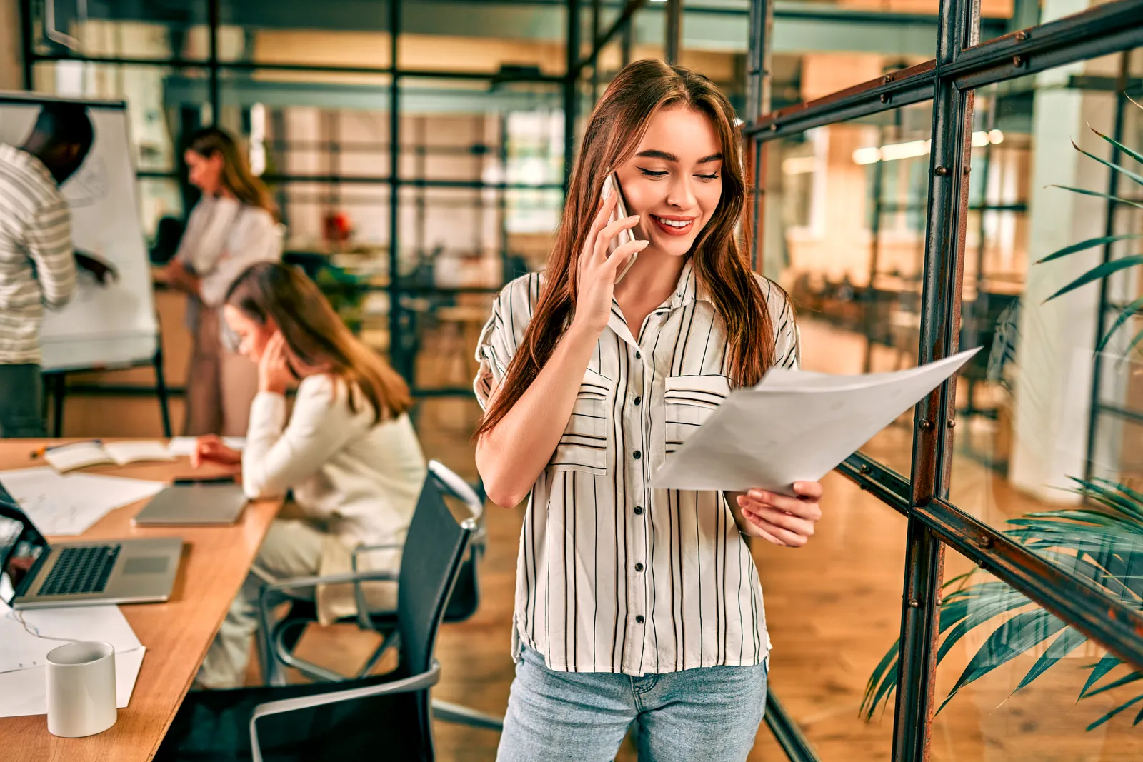 A smiling business owner talking on the phone in an office.